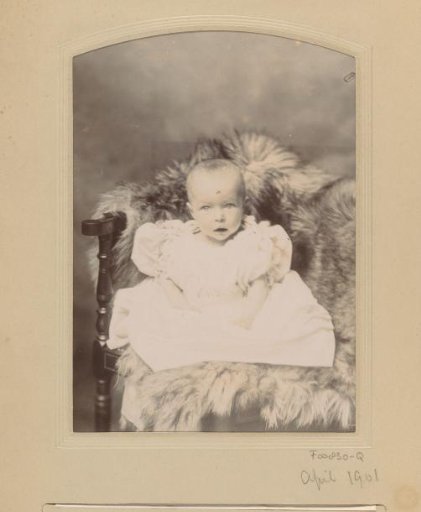 Portrait of a seated baby in a white dress