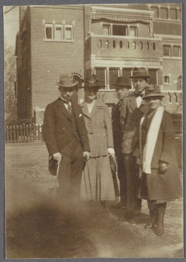 Group portrait of two women and three men in front of a brick building