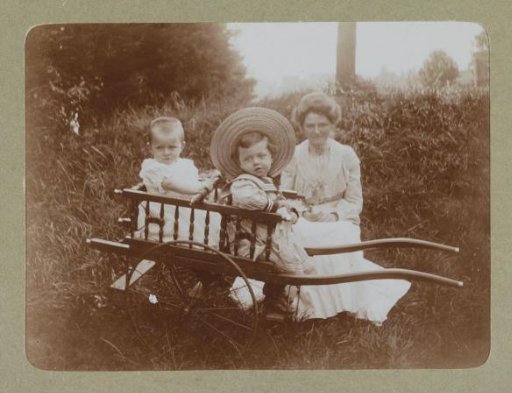 Woman with two toddlers with matching clothes and caps in a pushcart, probably the twins Ad and Johanna van der Kop and a family member