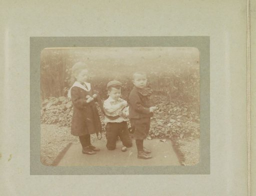 Three toddlers in a garden playing with a ribbon, probably the twins Ad (middle) and Johanna (left) and Han (right) van der Kop