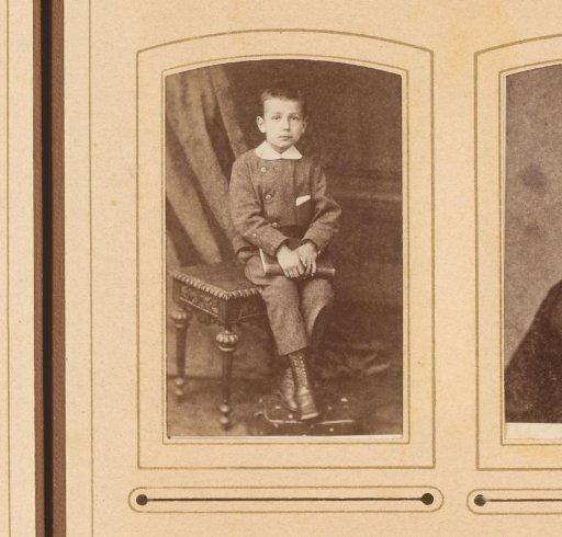 Portrait of a boy with a book on his lap, seated on a table