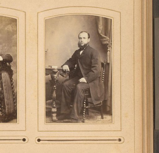 Portrait of a bearded man seated at a table