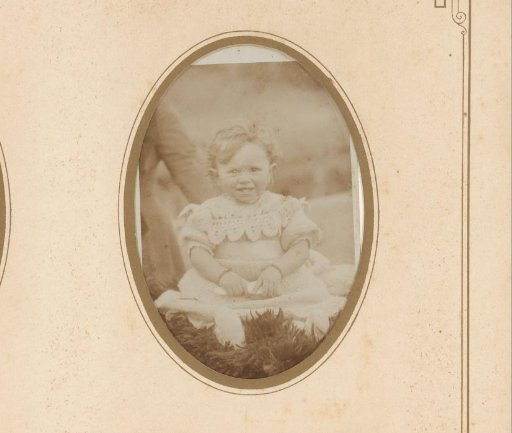 Portrait of a baby, seated but leaning on mother's arm