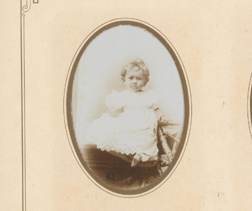 Portrait of a toddler in a knitted dress, seated on a fence