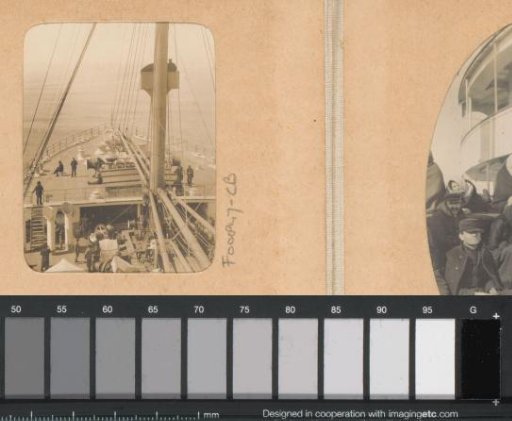 View of the foredeck of a ship with passengers, winches, and mast