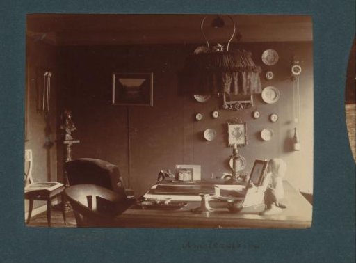 Interior of a room in Amsterdam with lamp, desk, busts, wall plaques, clock and (possibly) a photograph