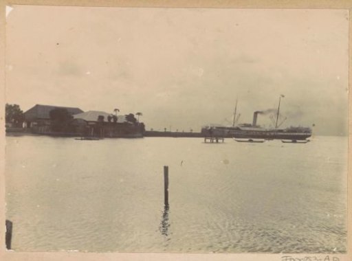 View of a bay with a ship and buildings on Ambon