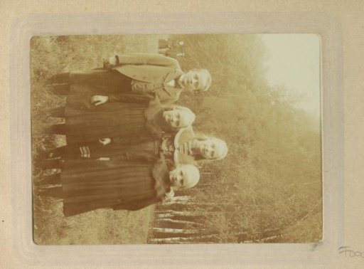 Group portrait of four children standing in a meadow in Germany with two adults in the background