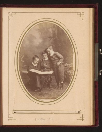 Group portrait of three boys reading in a book