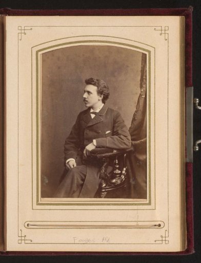 Portrait of a seated young man in a long coat