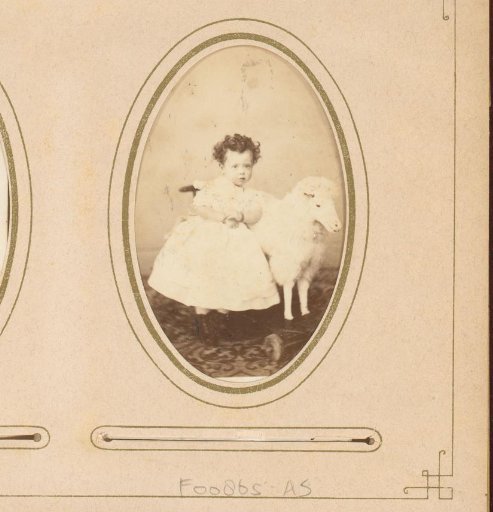 Portrait of a girl with a toy sheep on wheels