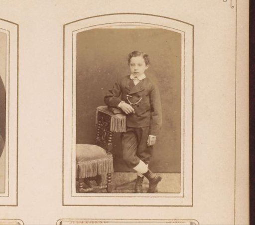 Portrait of a boy, standing by a chair