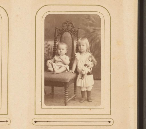 Portrait of a sitting baby and a standing girl holding a doll