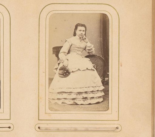 Portrait of a seated young woman holding a hat