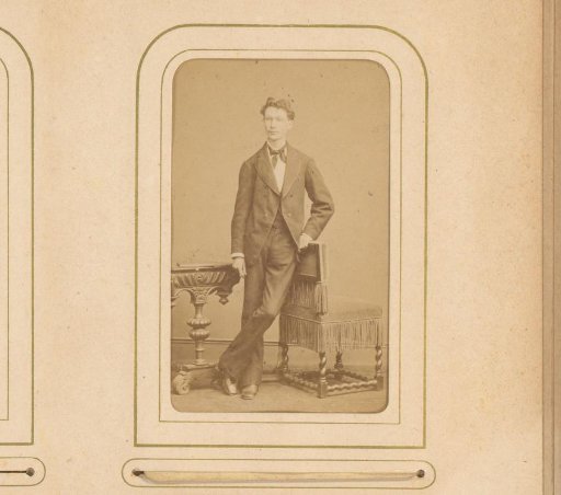 Portrait of a young man, standing by a table and chair