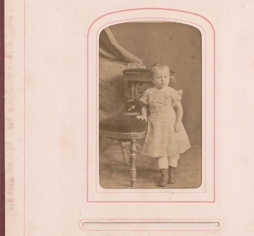 Portrait of a child standing by a chair
