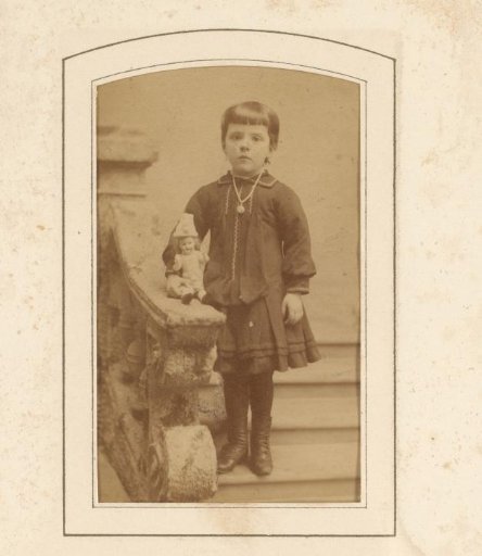 Portrait of a girl with a doll, standing on a staircase