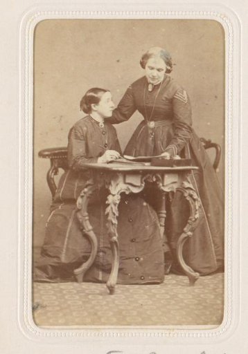 Portrait of two women at a table with writing materials
