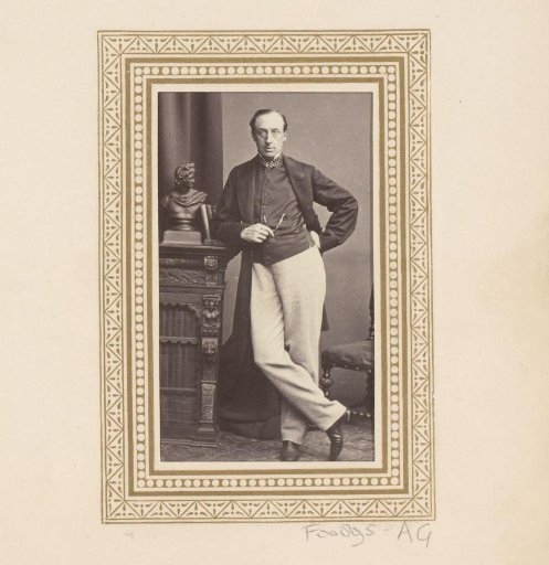 Portrait of a standing man leaning on a bookcase