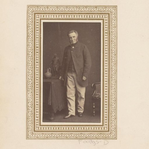 Portrait of a standing man beside a table with a sculpture