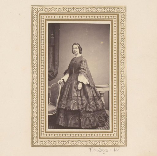 Portrait of a woman, standing by a chair