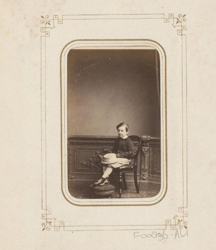 Portrait of a boy with a hat on his lap