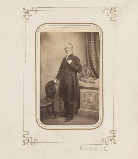 Portrait of a standing man by a chair