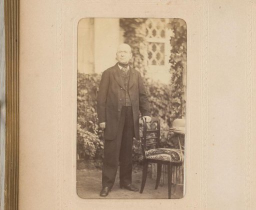 Portrait of a man standing by a chair in a garden