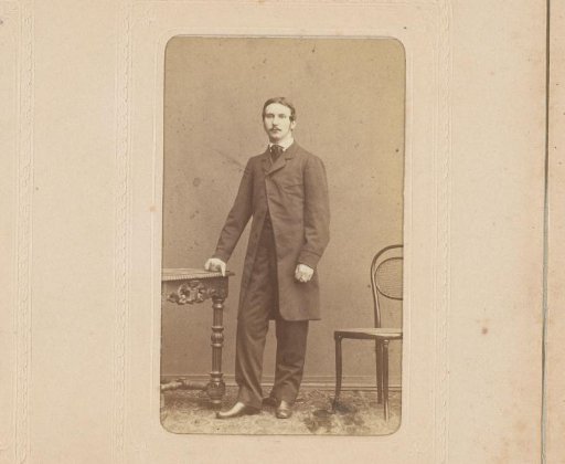 Portrait of a man with a mustache standing by a table