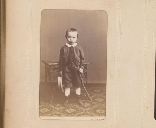 Portrait of a standing boy with a hat in his hand