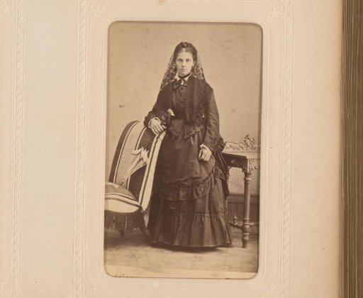 Portrait of a woman holding an umbrella, standing by a chair