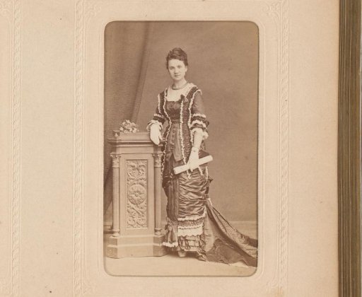 Portrait of a woman with a roll of paper in her hand, standing by a pillar