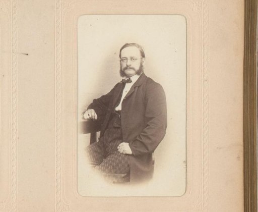 Portrait of a seated man with a moustache, sideburns and spectacles