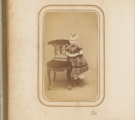 Portrait of a girl standing by a chair with a photo album