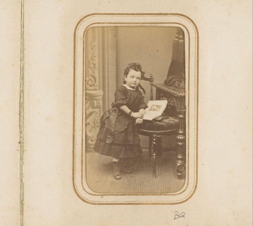 Portrait of a girl standing by a chair with a book