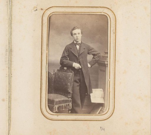 Portrait of a young man, standing by a chair