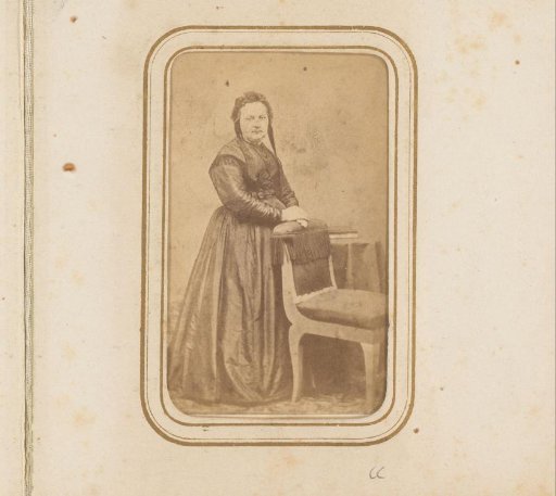 Portrait of an old woman, standing by a chair