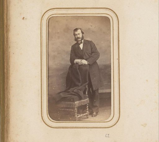 Portrait of a man, standing by a chair