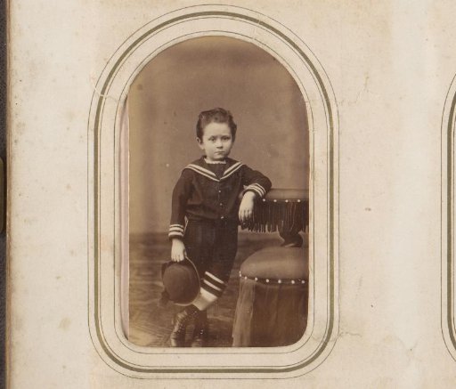 Portrait of a standing boy with a hat in his hand, leaning on a prayer stool