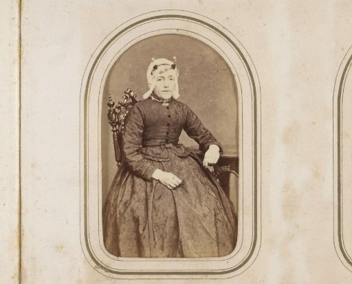 Portrait of a woman in a white traditional cap, seated at a table