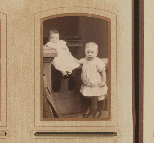 Portrait of a baby on a balustrade and a standing toddler