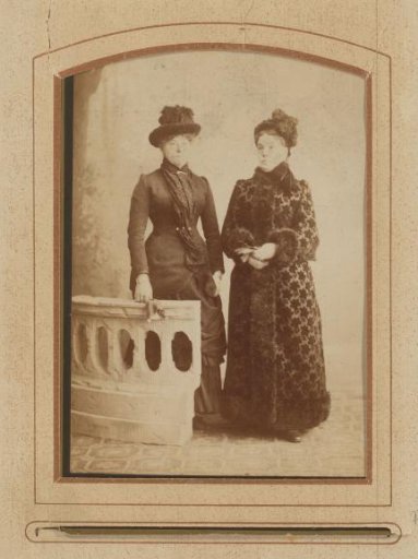 Portrait of two women with hats, standing by a balustrade