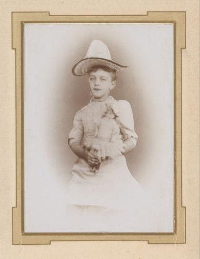 Portrait of a boy with a doll and a hat