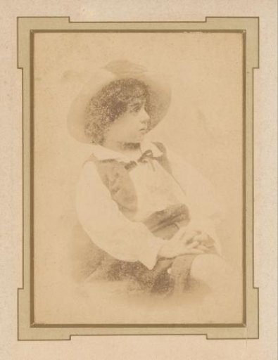 Portrait of a seated boy with a hat