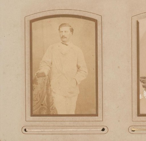 Portrait of a man with a mustache, standing by a chair
