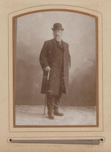 Portrait of a standing man with a hat, coat and walking stick