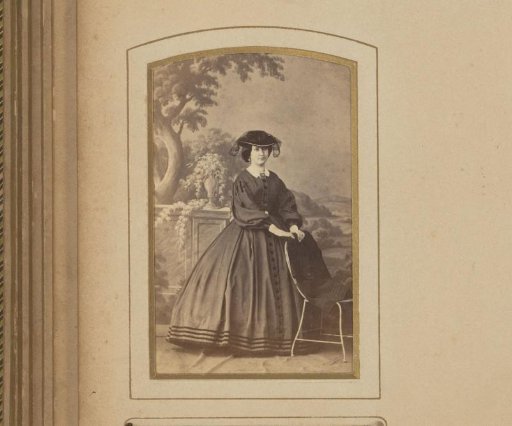 Portrait of a woman with a hat, standing by a chair