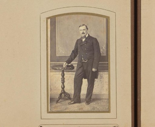 Portrait of a man in a frock coat, standing by a table