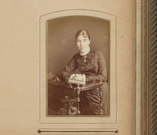 Portrait of a Standing Young Woman Leaning on a Table with a Book