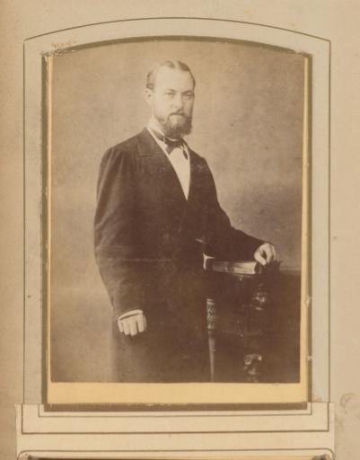 Portrait of a Man Standing Beside a Table with His Hand Resting on a Book